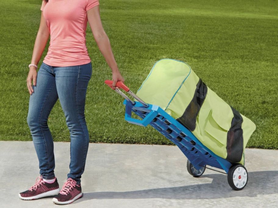 woman pulling along little tikes bounce house on hand cart
