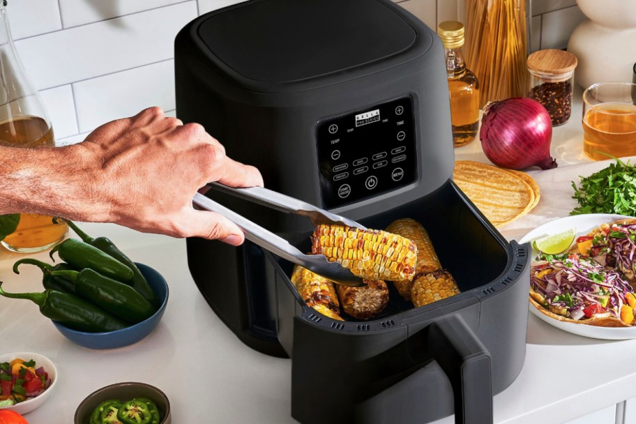 using tongs to grab roasted corn from air fryer