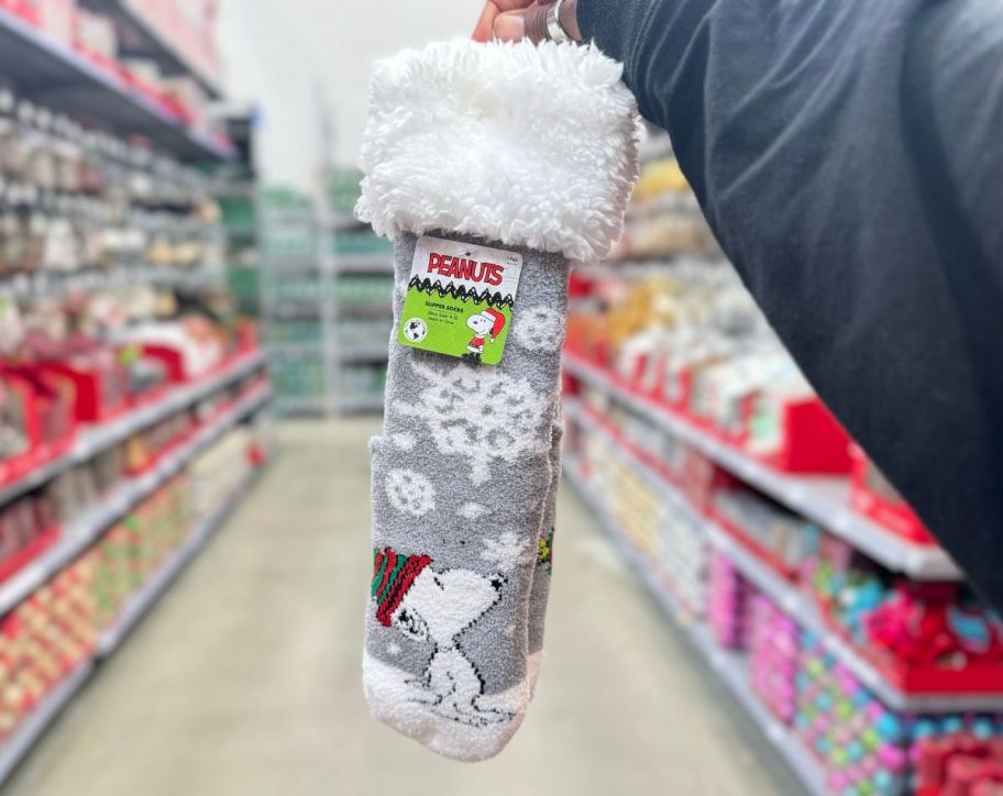a womans hand holding a pair of peanuts slipper socks