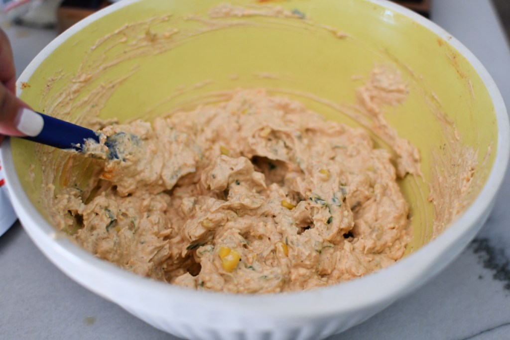 mixing up mexican corn dip in a bowl
