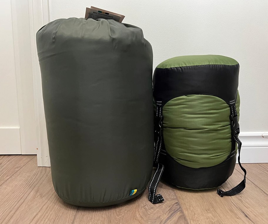 compression sacks with sleeping bags and clothes sitting on wood floor travel packing hacks