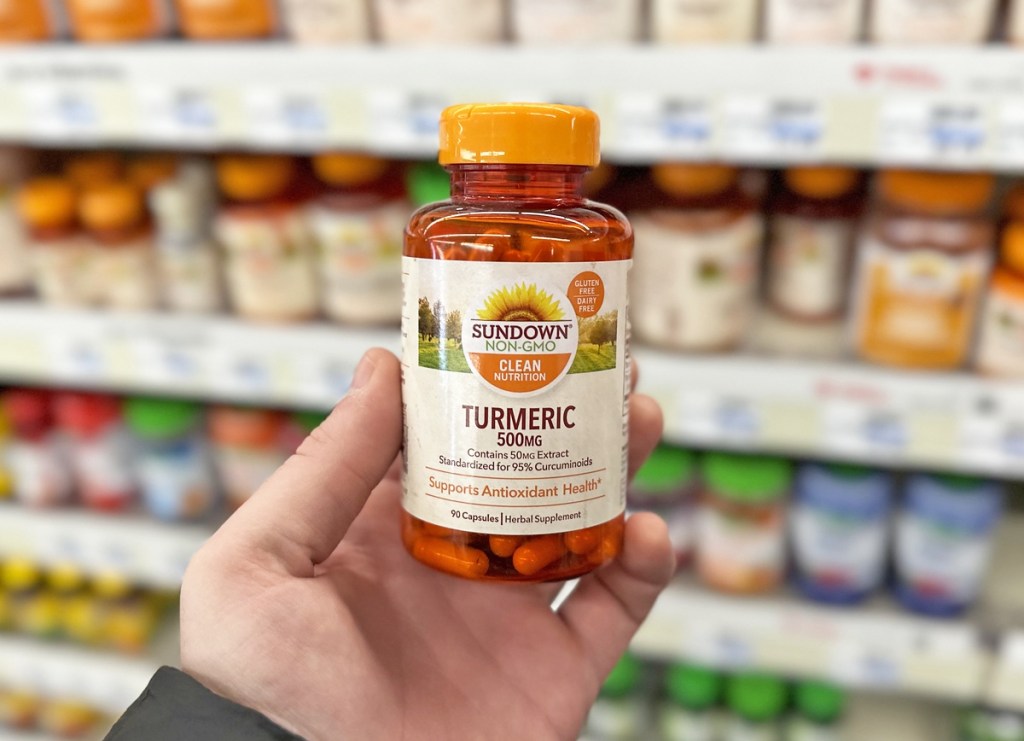 hand holding bottle of Sundown Naturals Turmeric supplement