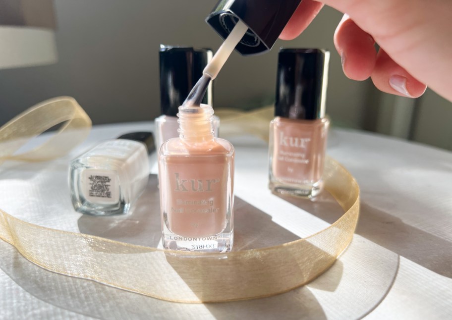 hand removing nail polish brush from bottle
