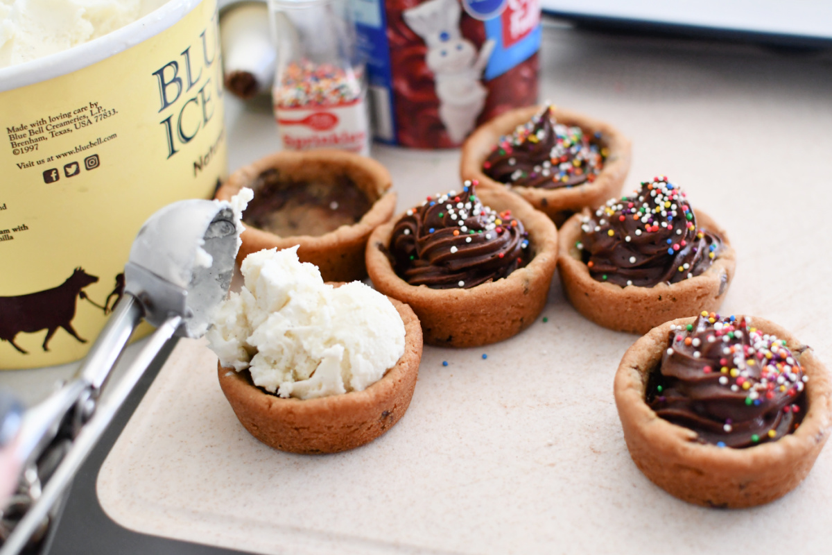 Adding Vanilla ice cream to the top of cookie. 