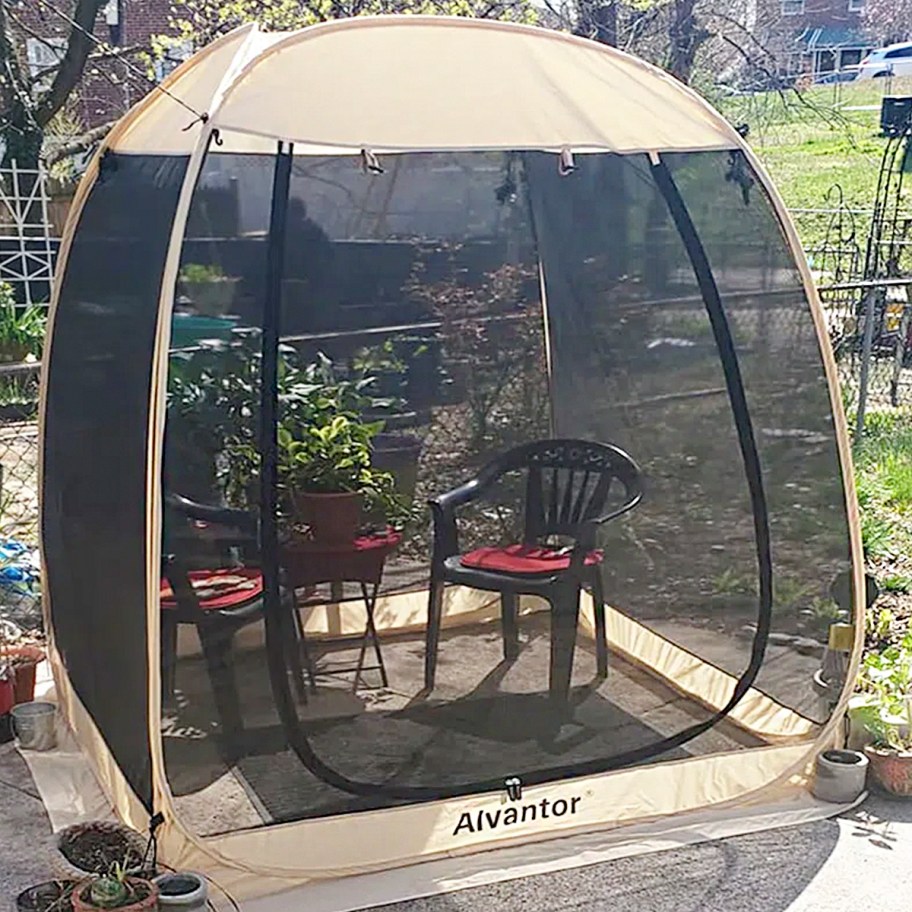 tan and black pop up tent with table and chairs inside