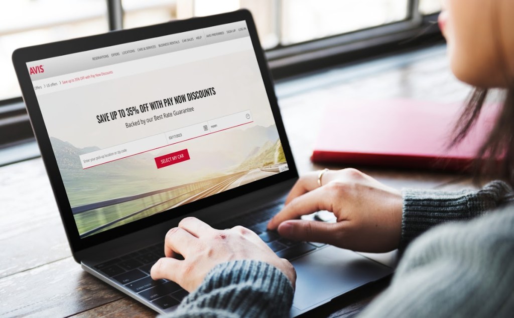 Woman looking at PAY NOW deals on the Avis Car Rental website because it sometimes is the cheapest way to rent a car