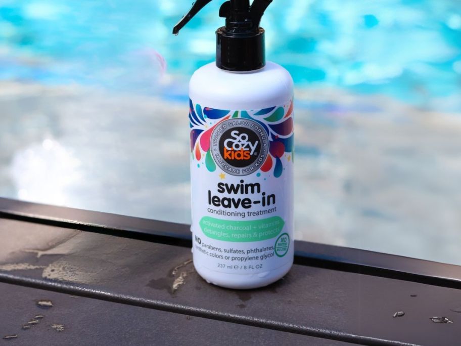 SoCozy Swim Spray Leave-In Conditioner 8oz bottle on ledge next to pool