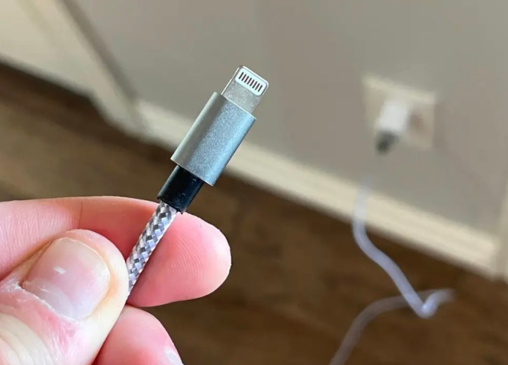 hand holding an extra long charging cord plugged into wall baby shower gift ideas