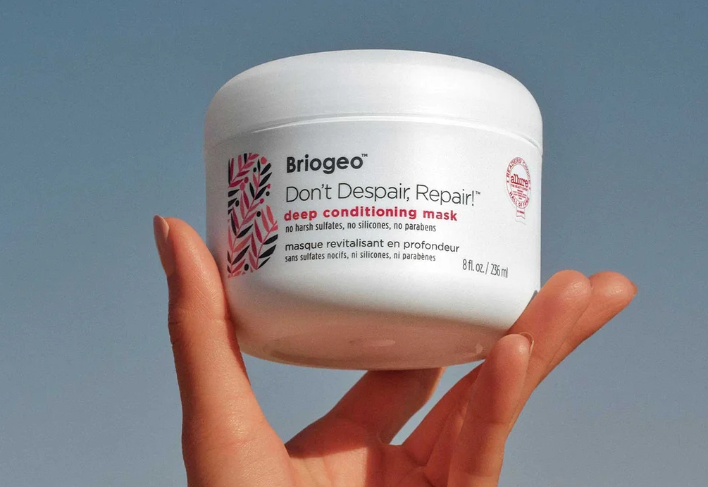 Hand holding a Briogeo Deep Conditioning Mask jar
