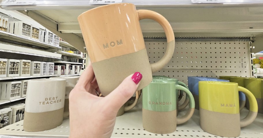 hand holding up a pink clay mug that says mom on it