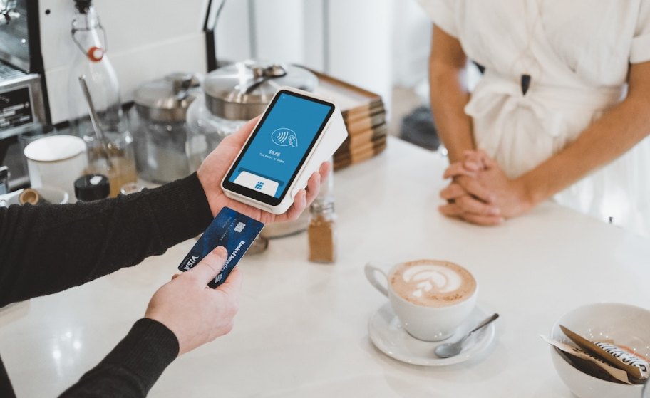 person inserting credit card into payment machine at coffee shop