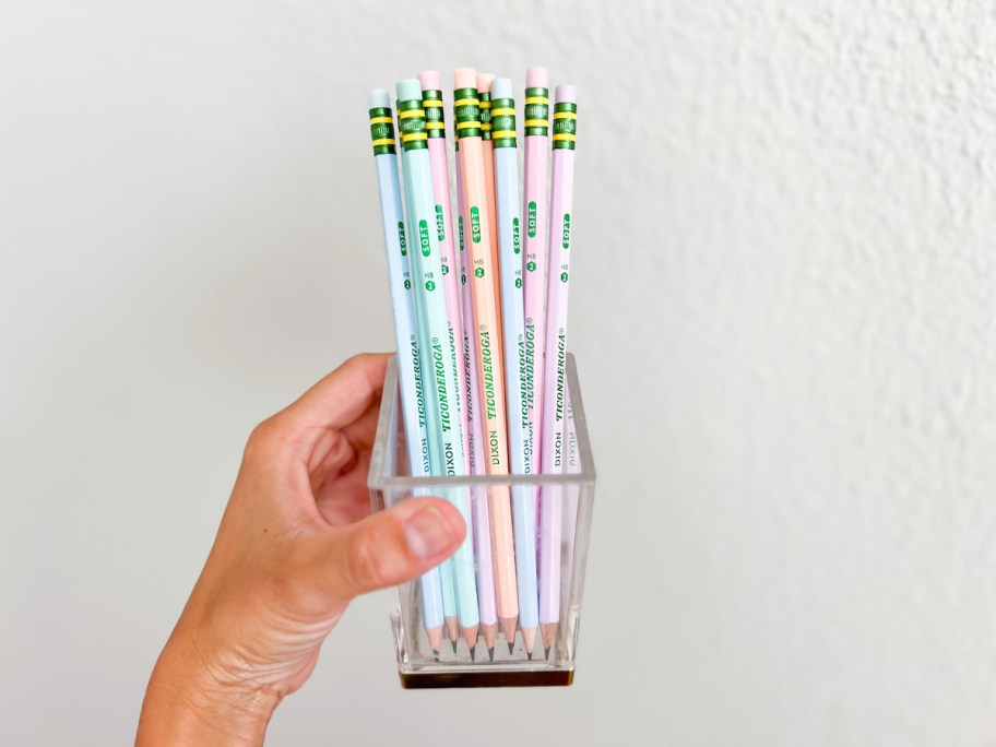 hand holding a clear jar of pastel pencils