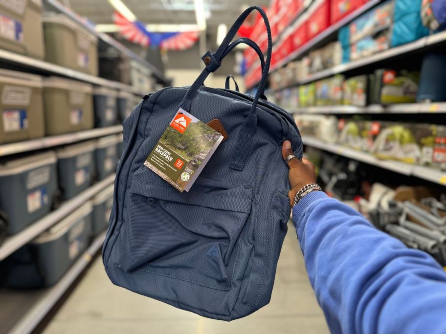 A person holding a blue backpack in a store