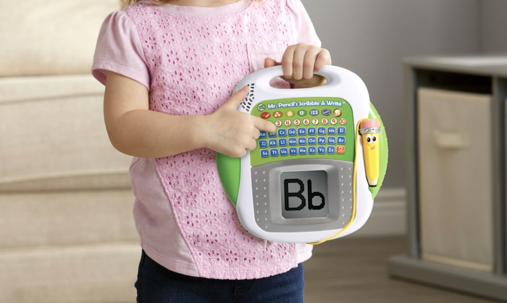 young girl pointing to a lLapFrog Scribble and Write toy 