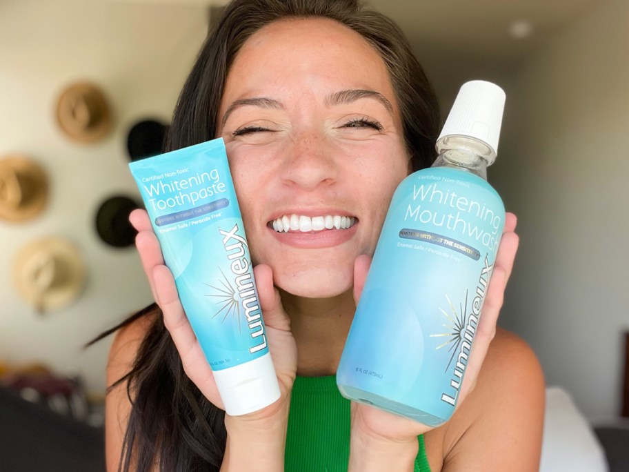 woman holding up Lumineux toothpaste and mouthwash