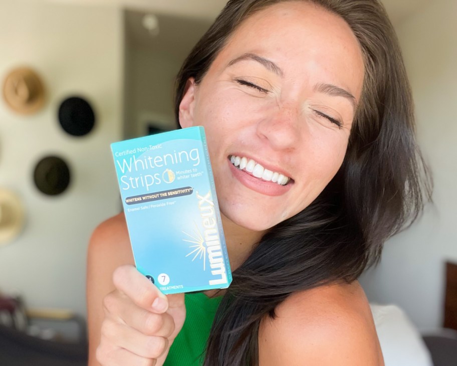 woman holding up a box of Lumineux Teeth Whitening Strips