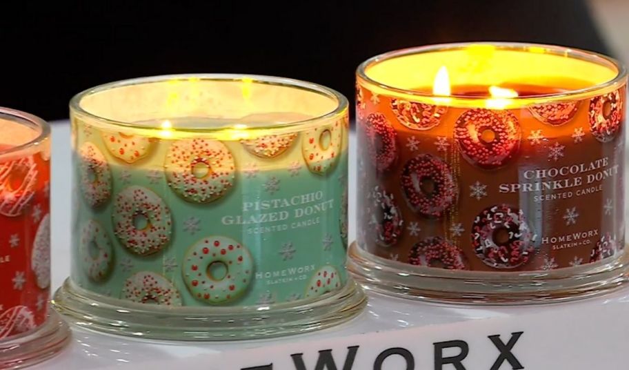 a close up of two lit scented 3-wick candles