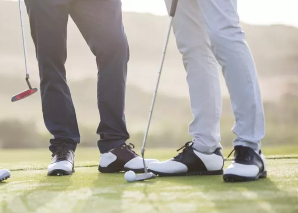 two men standing on golf green with clubs
