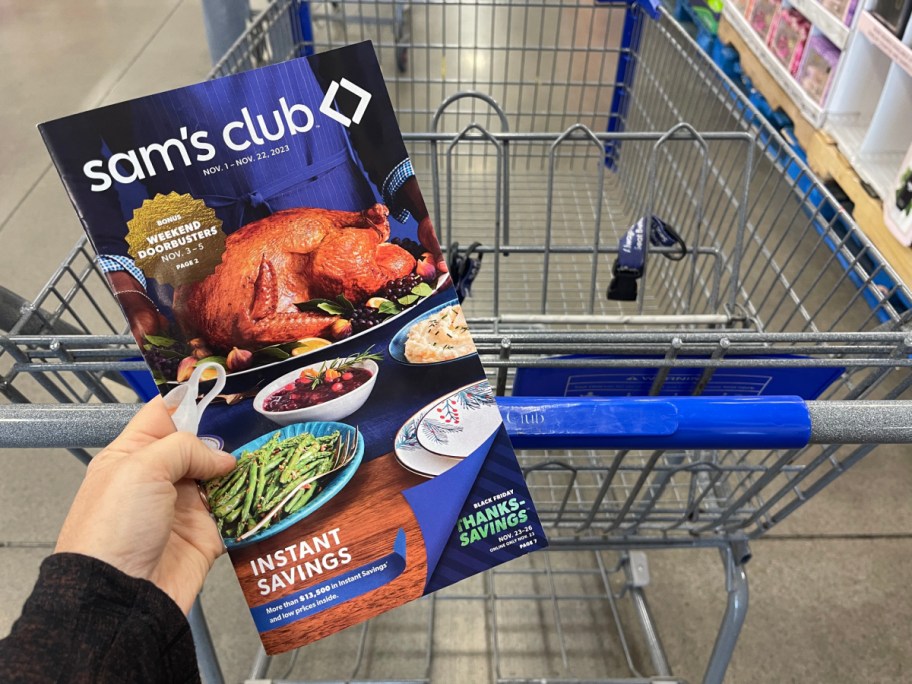 woman holding Sams Club Instant Savings Booklet in store with cart