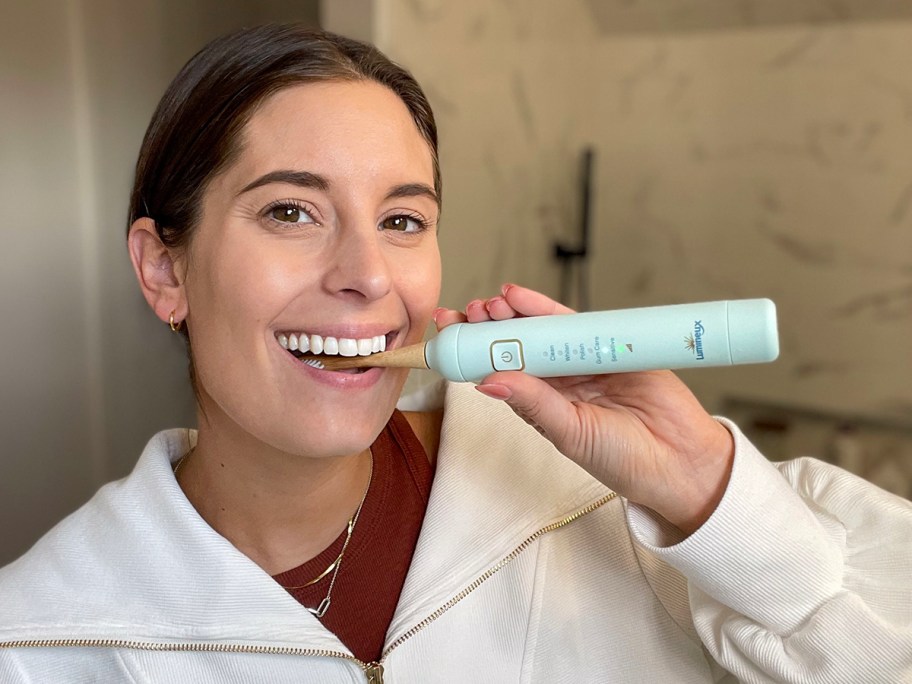 woman brushing teeth with teal lumineux toothbrush