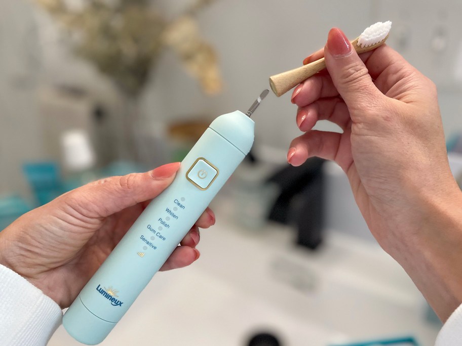 hand putting brush head on toothbrush