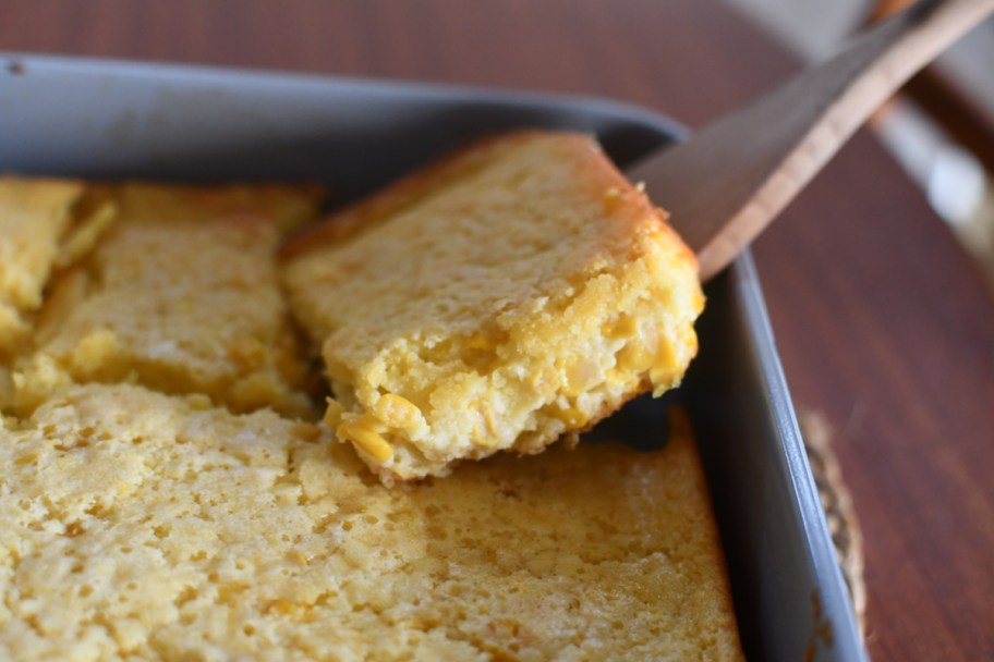 Taking a slice of Jiffy Cornbread Casserole from a baking dish