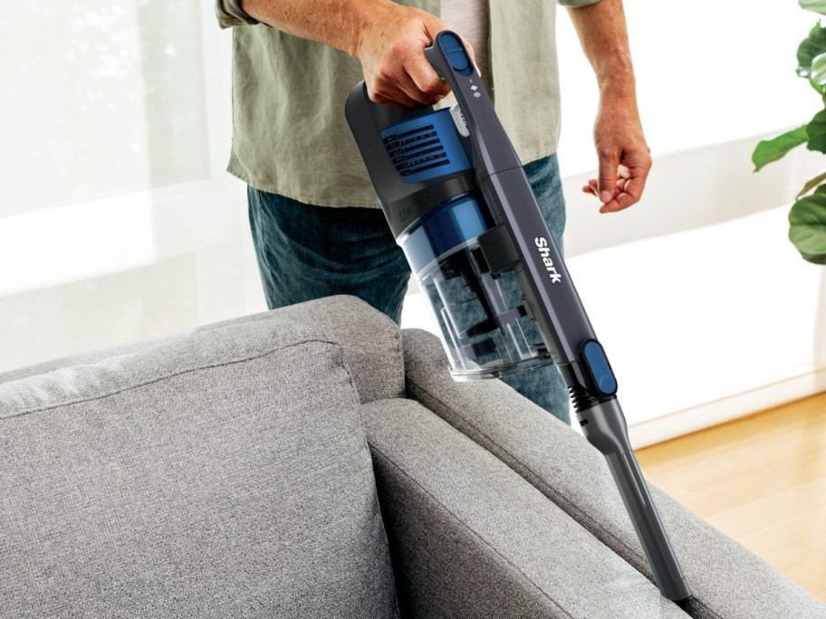 Man, vacuuming, grey couch with shark handheld vacuum