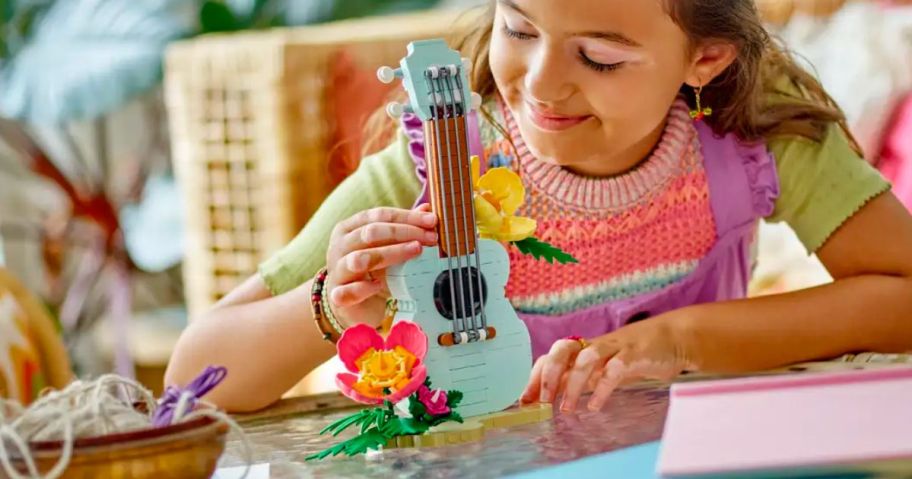a little girl admiring her work on the Lego creator 3-in-1 Tropical Ukulele set