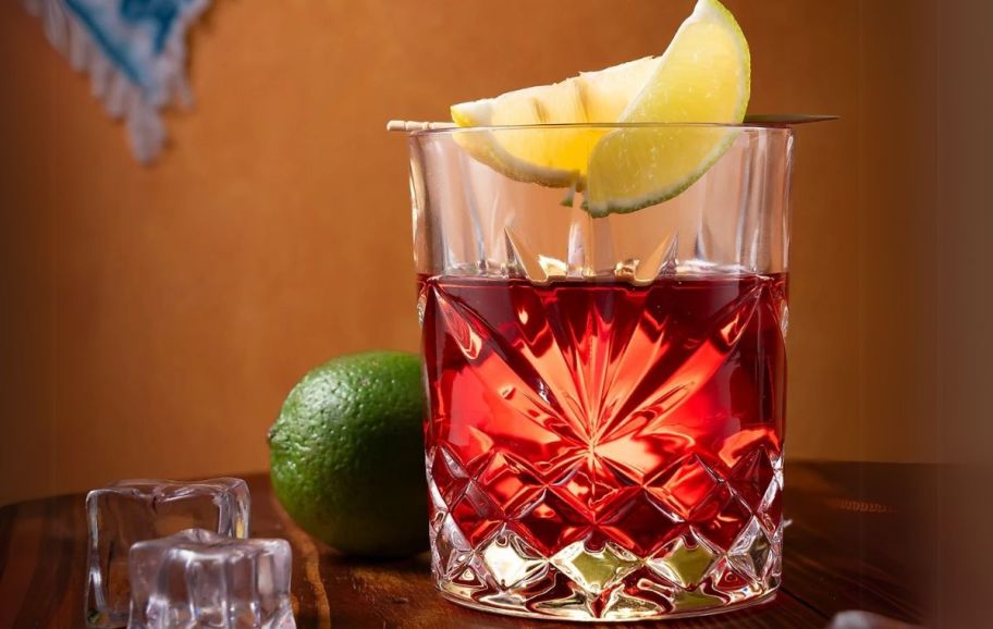 a drink served in an old-fashioned glass with a lemon wedge