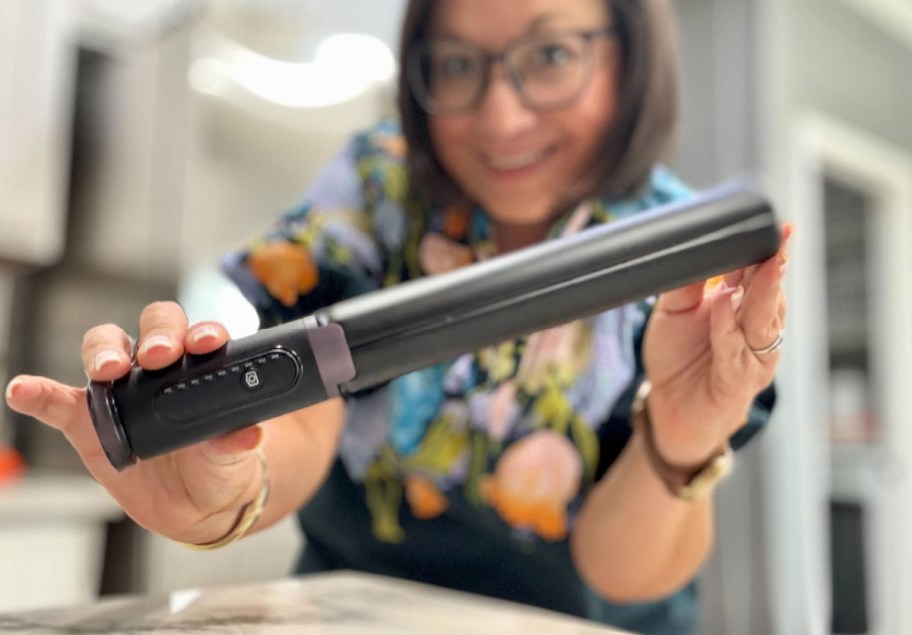 woman holding her phone tripod all folded up showing it to the camera