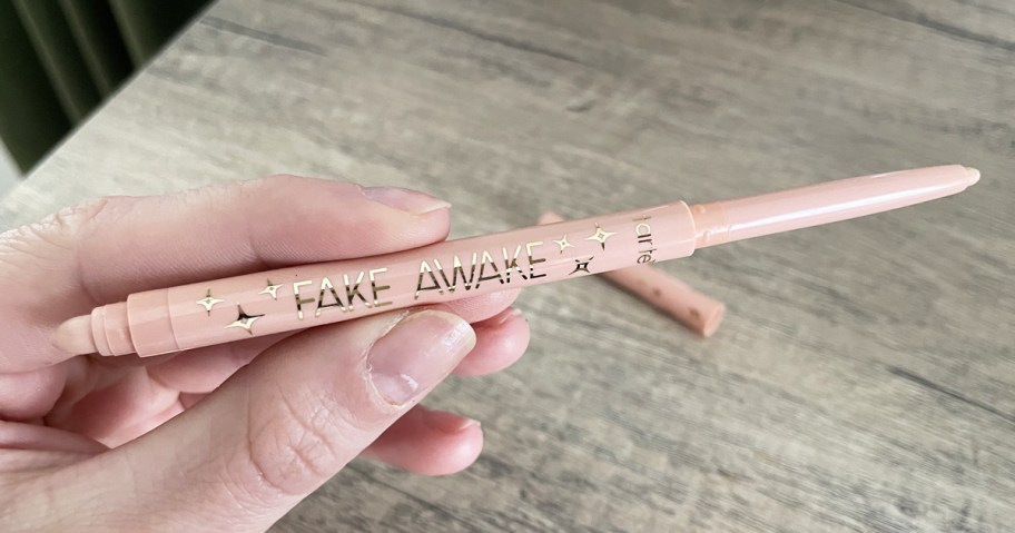 hand holding prink stick of Tarte Fake Awake Eye Highlight