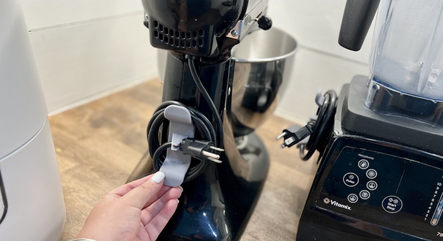 hand holding edge of cord organizer on kitchen appliance