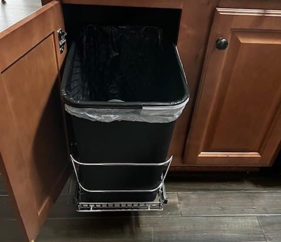 black trash can inside of wooden kitchen cabinet