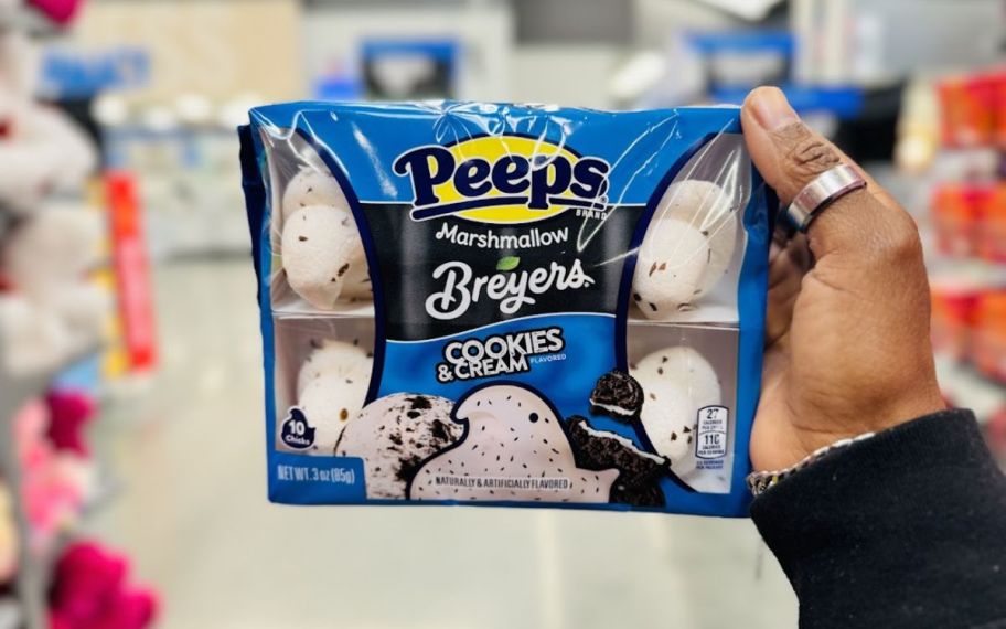 a womans hand holding a package of cookies and cream ice cream peeps