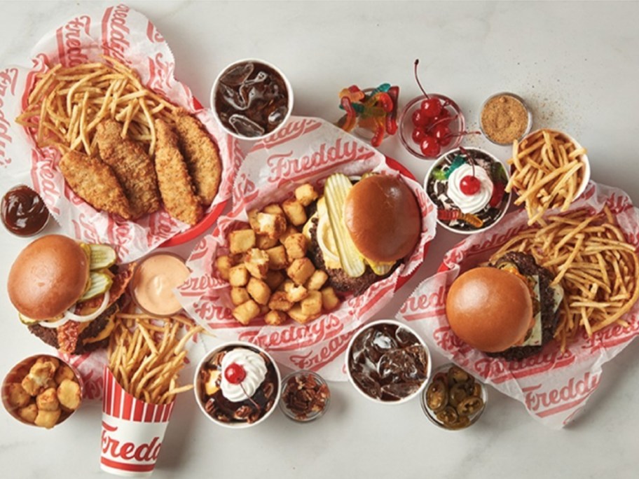 meal platters with burgers and fries, chicken sandwich and tots, chicken tenders and fries, ice cream sundaes, ice cream shakes, cups of soda from Freddy's restaurant