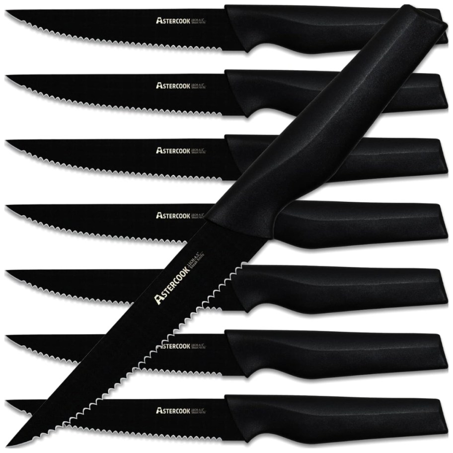 a set of 8 black stainless steel steak knives - one is laying on top of the other seven