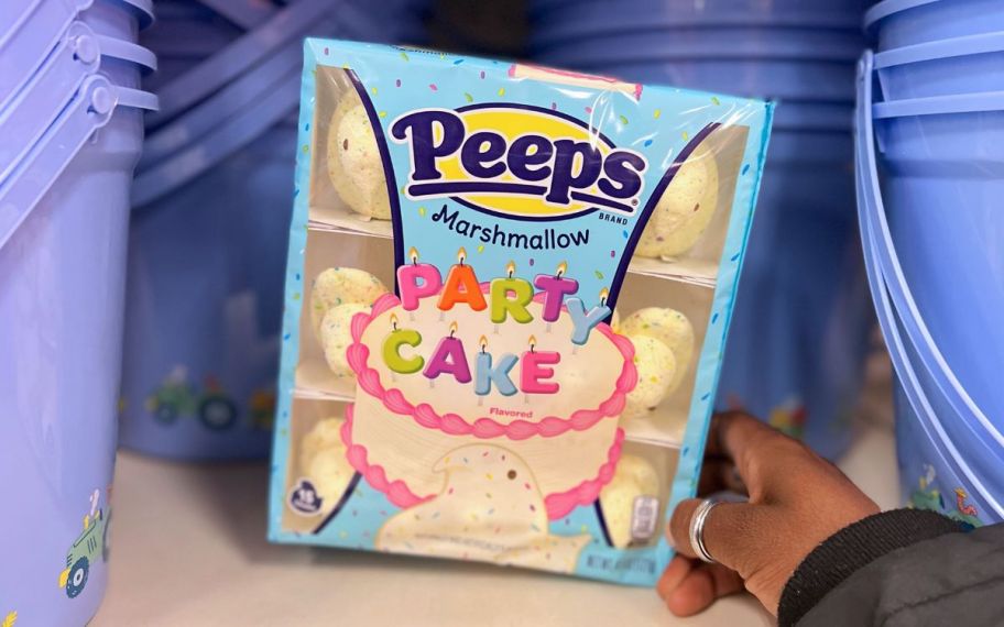 a womans hand holding a package of party cake peeps