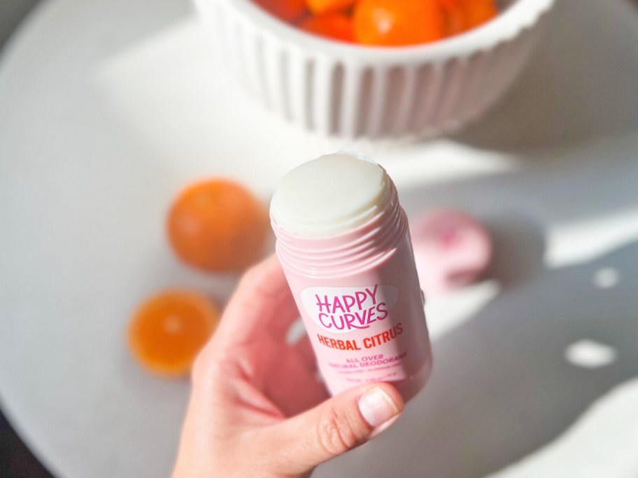 hand holding an opened pink stick of deodorant