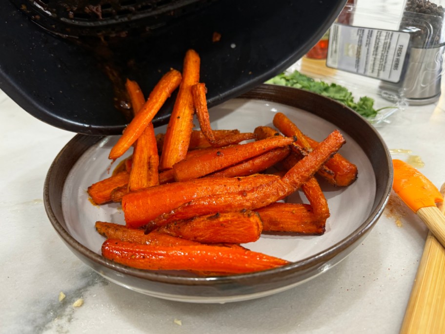 adding carrots to a plate after cooking in an air fryer