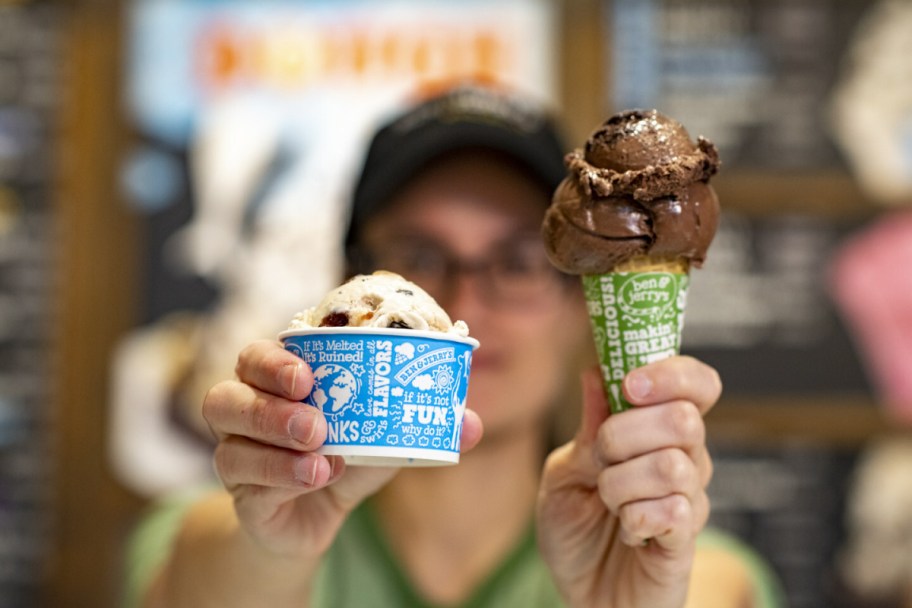 ben and jerrys employee holding up a cone and cup of their ice cream