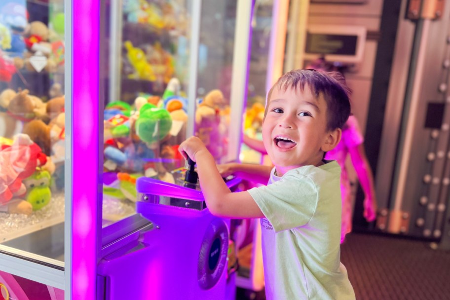 little boy smiling at claw machine