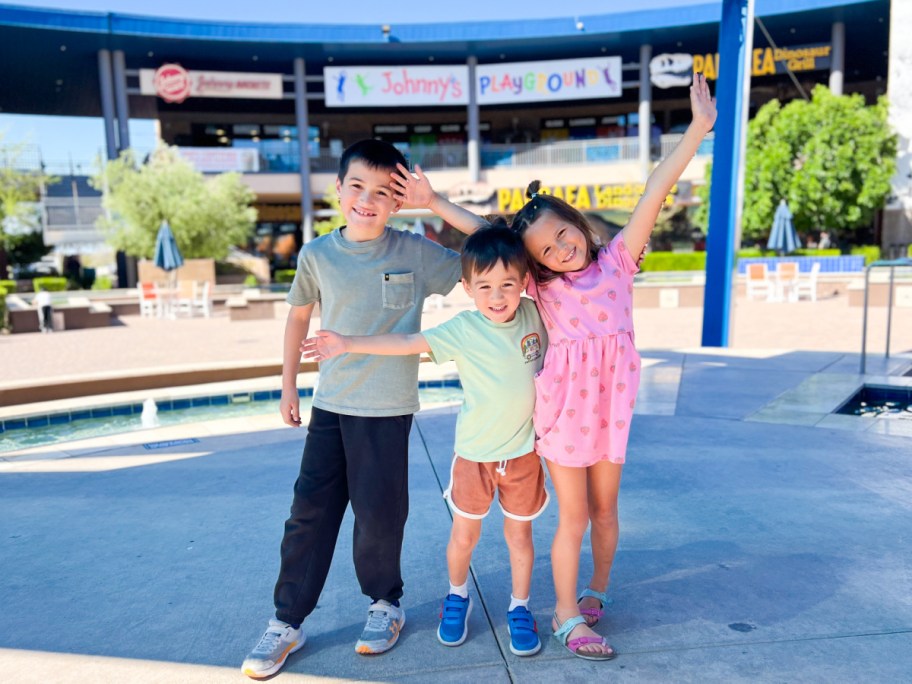 three kids standing under canopy looking excited