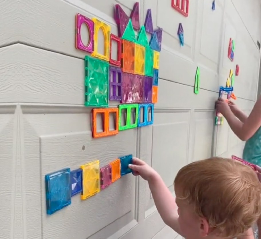kids putting magnet tiles on garage door