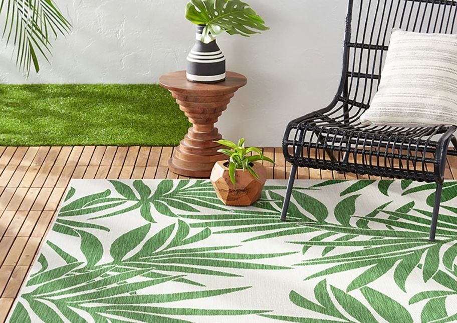 a green and white patio rug shown on a wooden deck with a chair