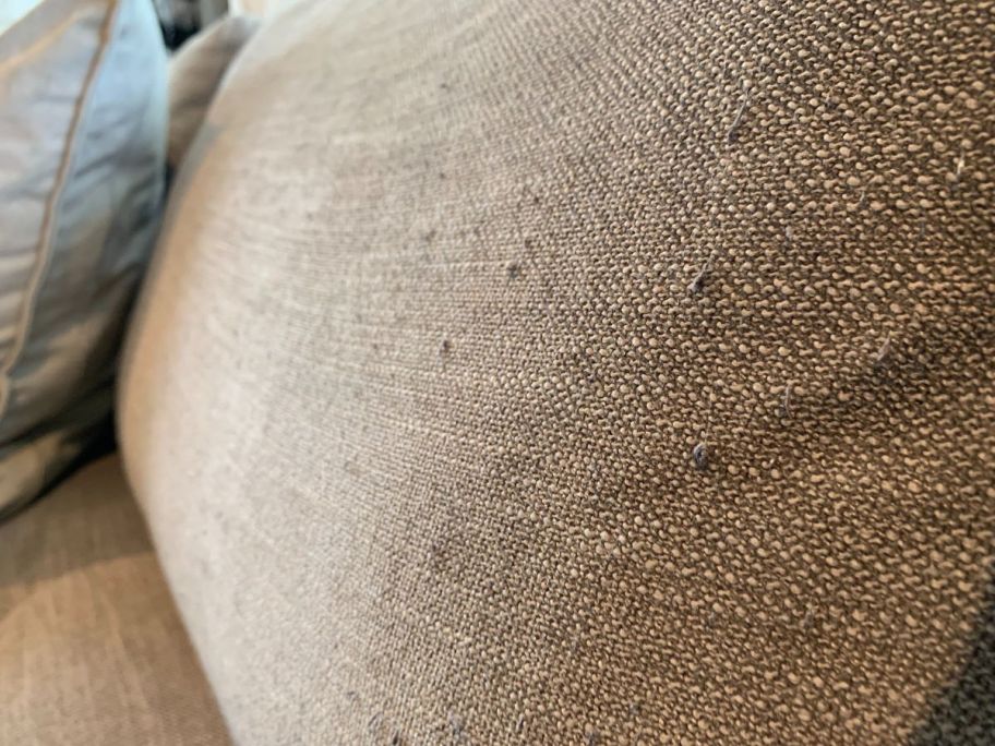 A couch cushion with pilling is shown before using the fabric shaver.