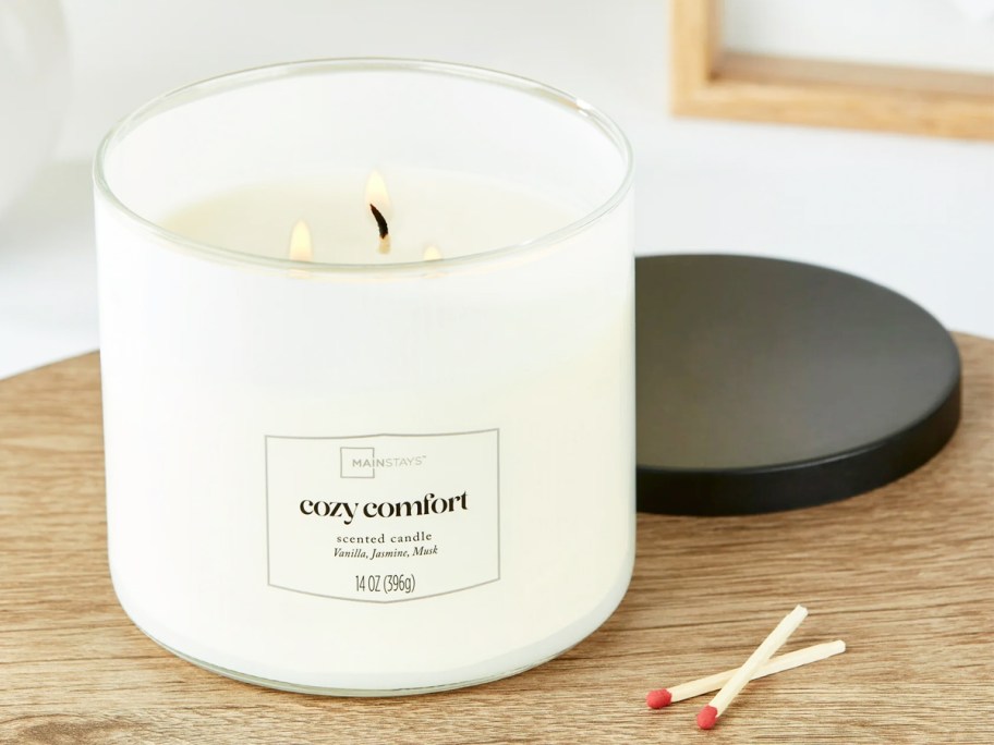 lit white candle on a wood table