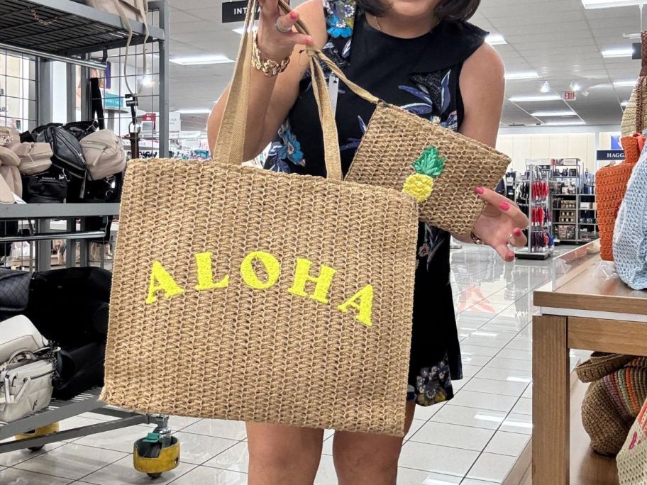 A woman holding a straw tote with the word "Aloha" on it 