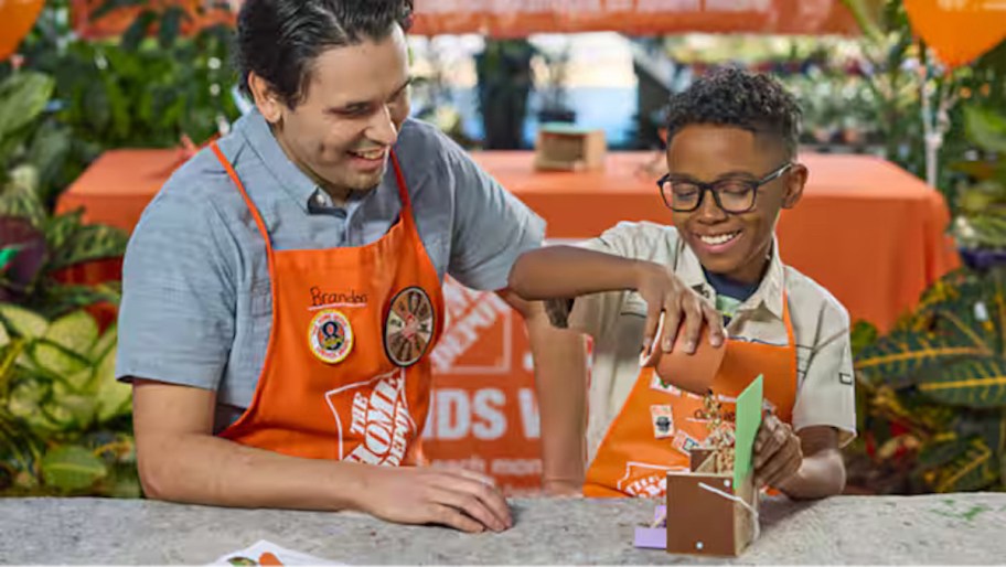 boy and man sitting at home depot work bench with aprons