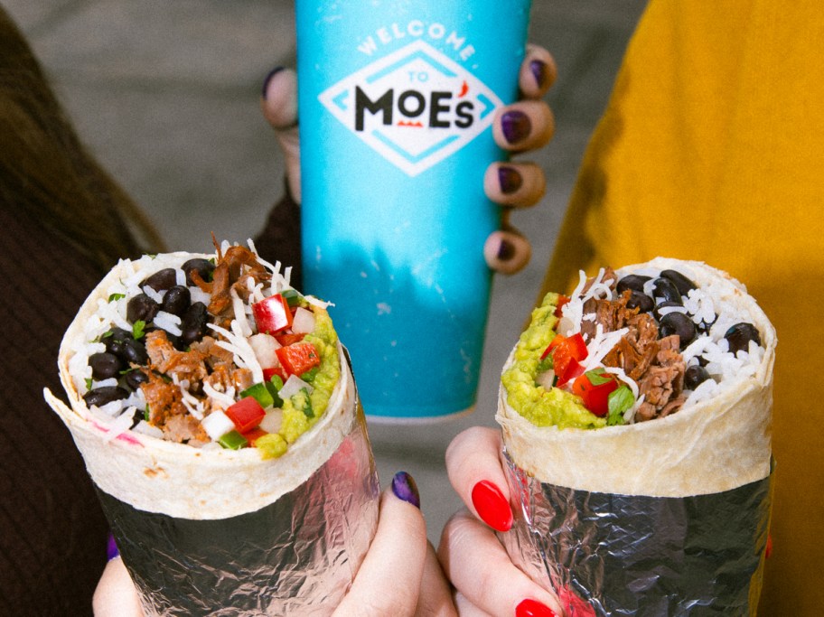 holding 2 burritos and a fountain drink from Moe's