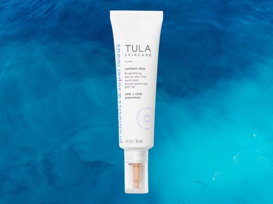 TULA Radiant Skin Brightening Serum Skin Tint SPF 30 against blue background